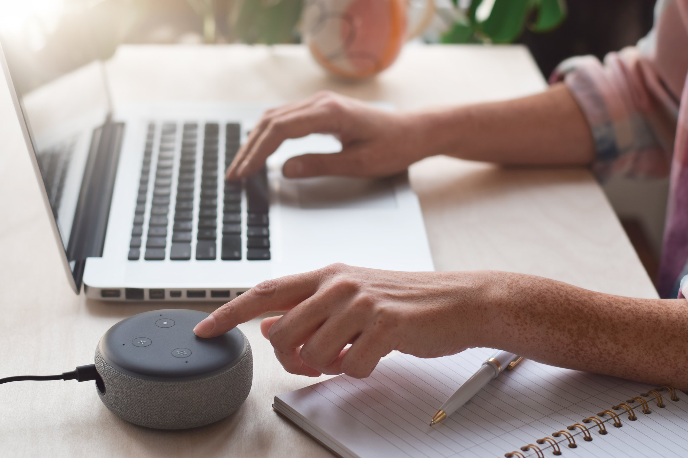 Woman sitting at desk using virtual assistant smart speaker